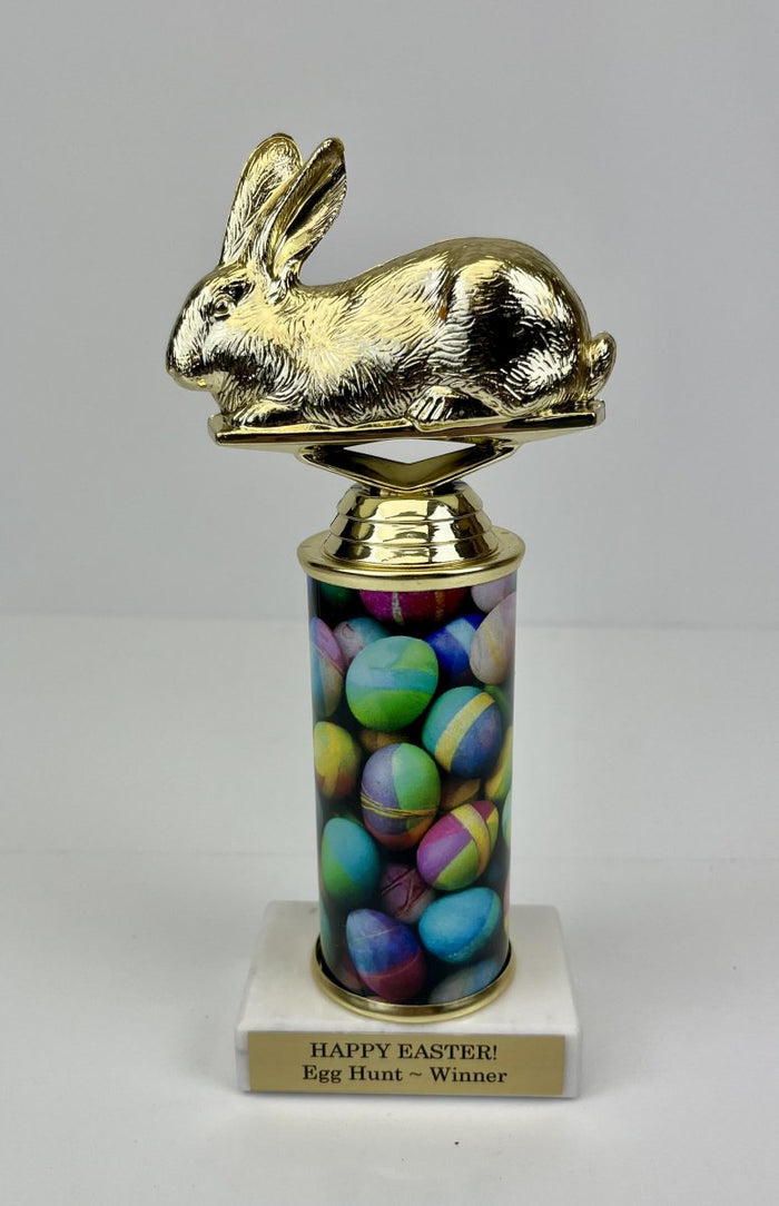 An Easter-themed trophy featuring a golden bunny figure on top of a column with colorful Easter egg graphics, mounted on a white marble base with a trophy plate.