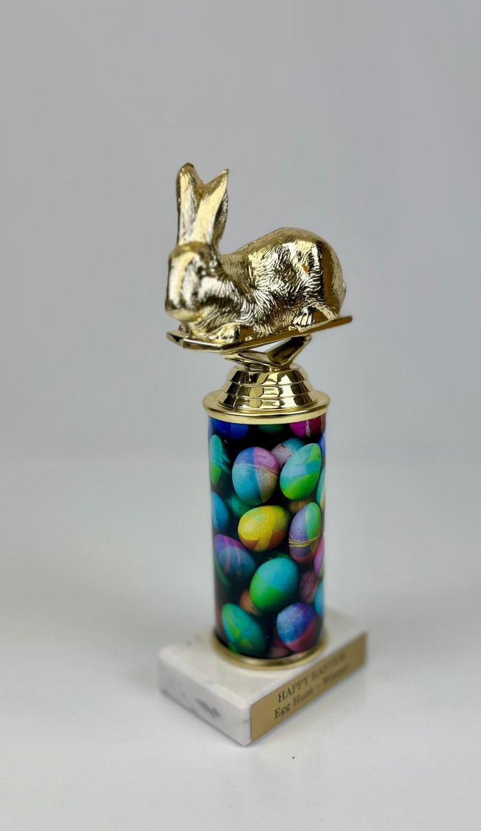 An Easter-themed trophy featuring a golden bunny figure on top of a column with colorful Easter egg graphics, mounted on a white marble base with a trophy plate.