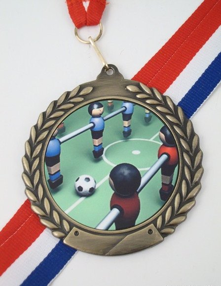 A gold medal with a custom Foosball logo in the center, featuring red, white, and blue neck ribbon.