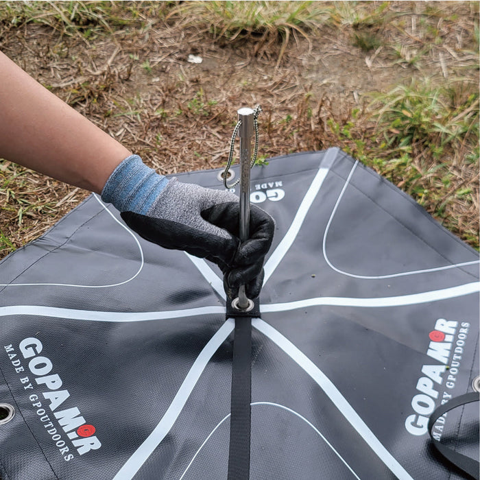 Close-up of a hand inserting the metal center pin through the G450 guy-line webbing anchor pad grommet