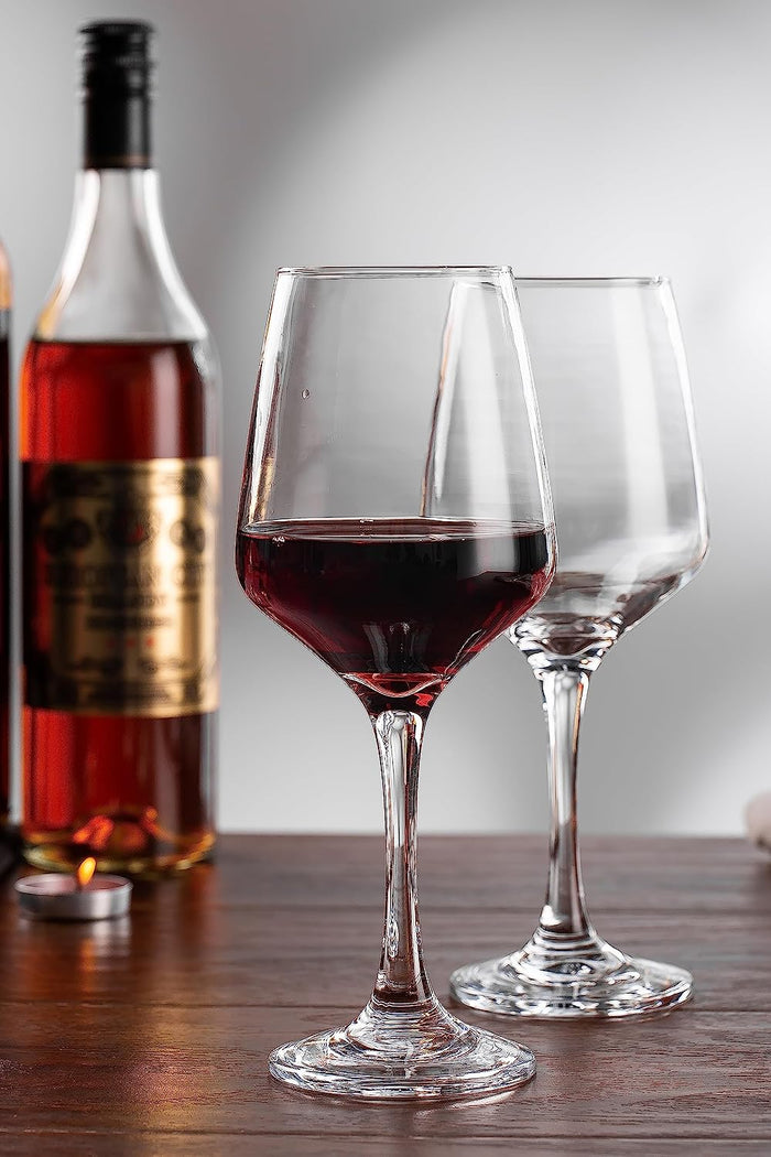 Wine glass filled with red wine, placed on a table.